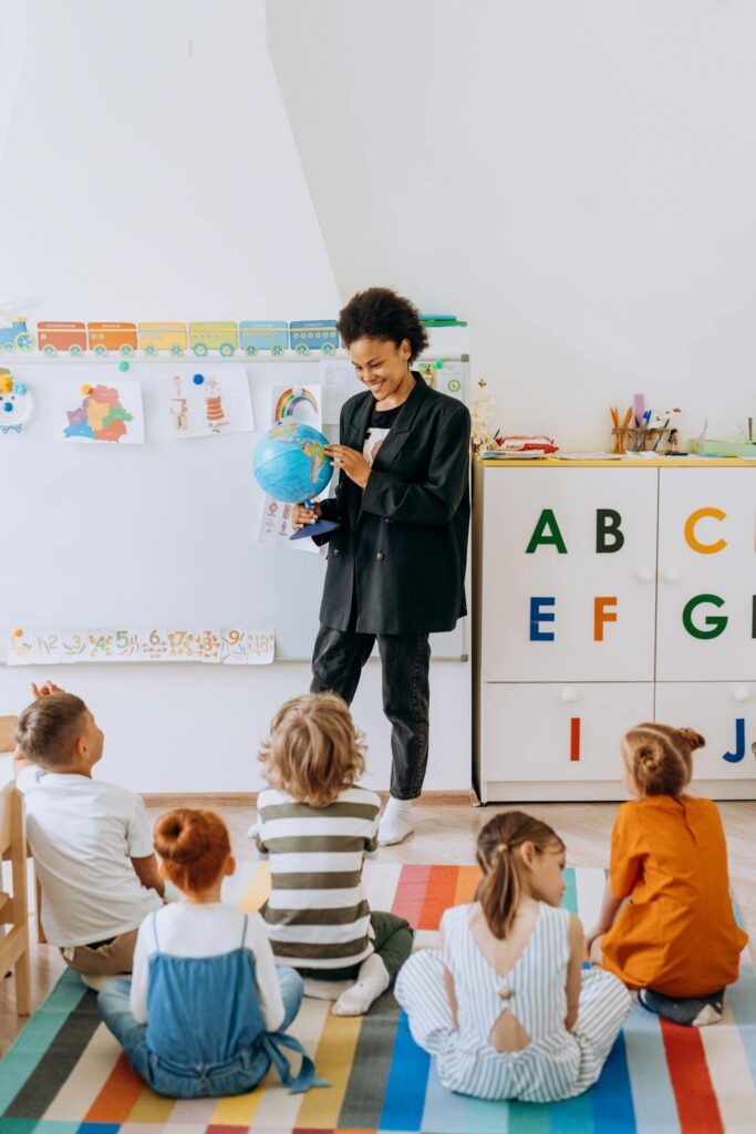 A teacher engaging preschool children with a globe in a classroom setting.